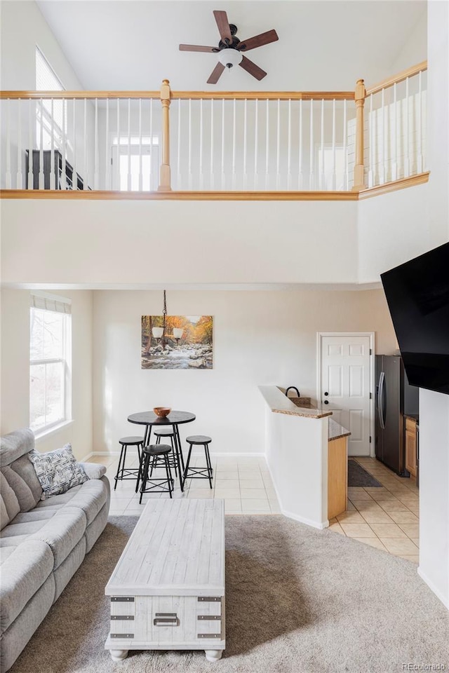 unfurnished living room featuring a towering ceiling, light tile patterned floors, and ceiling fan