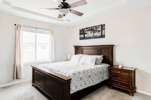 bedroom with light colored carpet, ceiling fan, and a tray ceiling