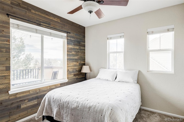 carpeted bedroom featuring ceiling fan and wooden walls