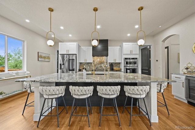 14950 W 32nd Ave, Golden, CO 80401 - kitchen with stainless steel appliances, decorative backsplash, white cabinetry, beverage cooler, and a large island