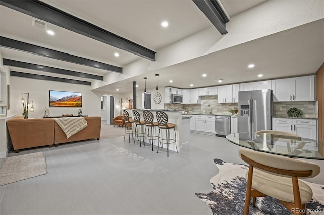 14950 W 32nd Ave, Golden, CO 80401 - kitchen with open floor plan, appliances with stainless steel finishes, backsplash, beamed ceiling, and a kitchen breakfast bar