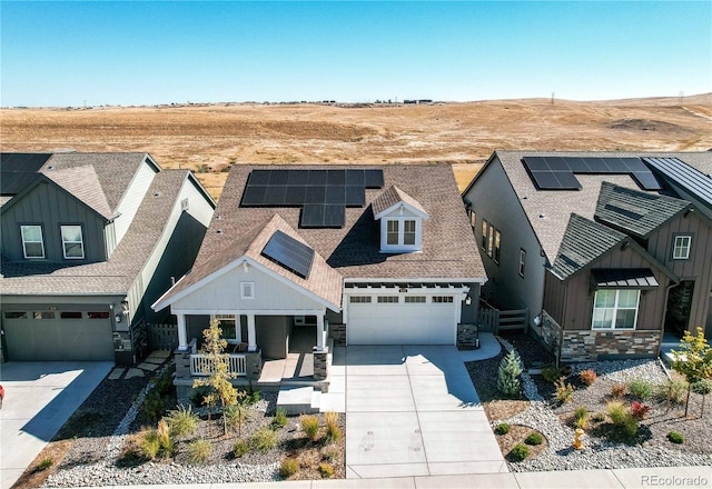 view of front of property featuring a garage, solar panels, and covered porch