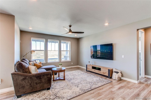 living room featuring a textured ceiling, ceiling fan, and light hardwood / wood-style flooring