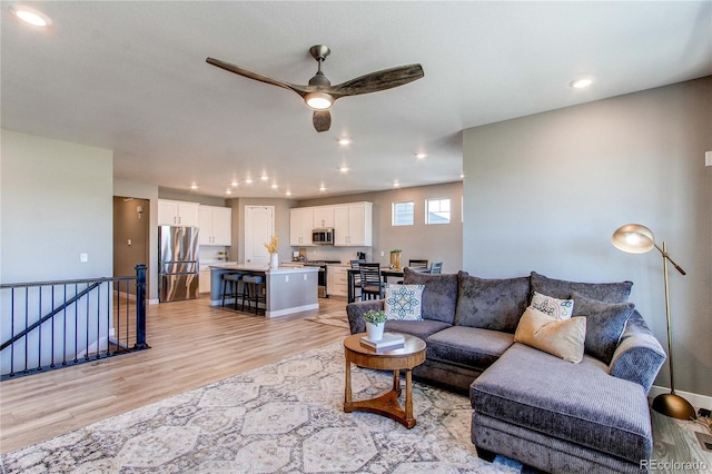 living room with ceiling fan and light wood-type flooring