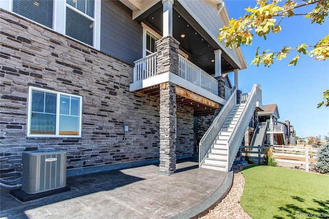 exterior space with a balcony, a yard, a patio, and central AC