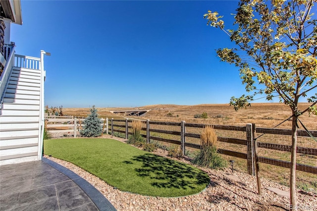 view of yard with a rural view and a patio area