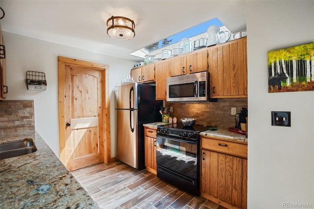 34 Nebraska Cir, Florissant, CO 80816 - kitchen featuring light stone counters, stainless steel appliances, a sink, decorative backsplash, and light wood-style flooring