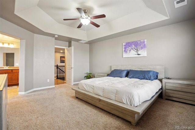 bedroom featuring a tray ceiling, a sink, visible vents, and baseboards