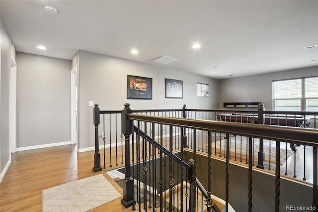 hallway with recessed lighting, baseboards, an upstairs landing, and wood finished floors