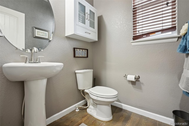 half bathroom with a sink, wood finished floors, toilet, and baseboards