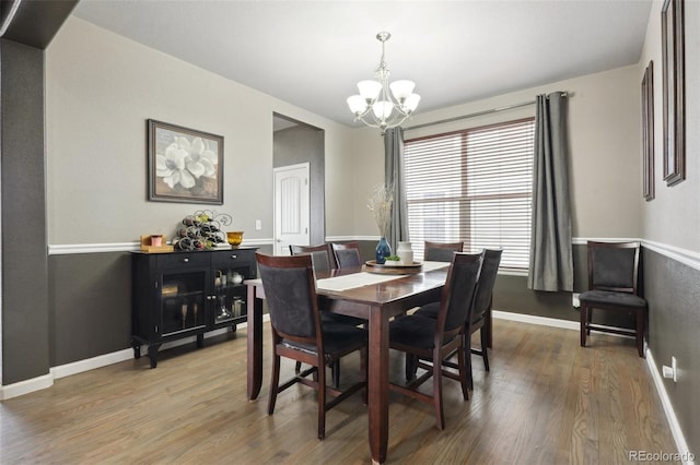 dining room with a chandelier, wood finished floors, and baseboards