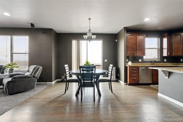 dining space featuring a textured ceiling, baseboards, and wood finished floors