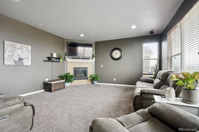 living area featuring a tile fireplace, baseboards, carpet, and recessed lighting