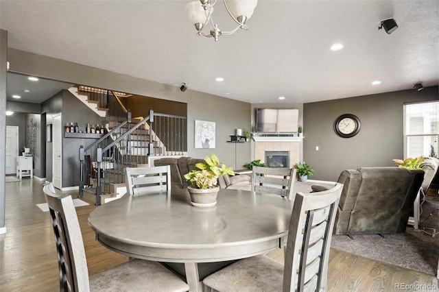 dining area with light wood finished floors, stairs, a fireplace, and recessed lighting