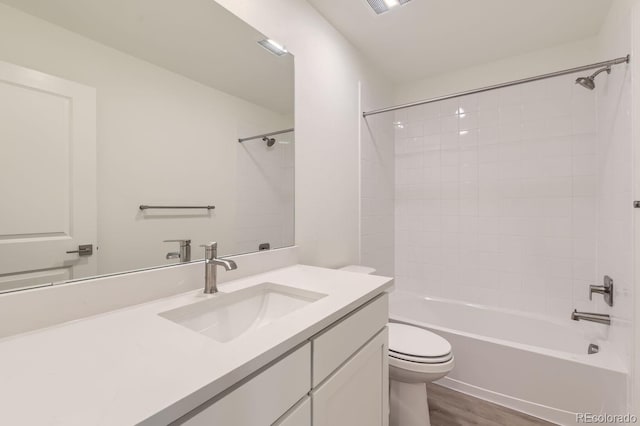 full bathroom featuring tiled shower / bath, vanity, toilet, and hardwood / wood-style floors