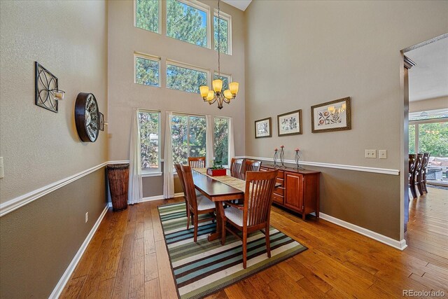 10421 Kennemere Ln, Parker, CO 80134 - dining room with a chandelier, hardwood / wood-style flooring, a towering ceiling, and a textured wall