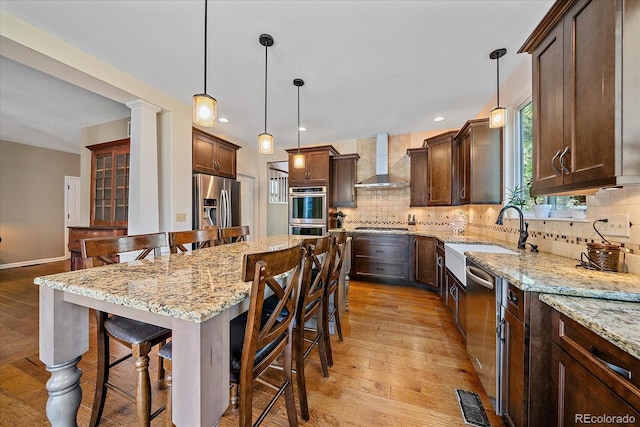 10421 Kennemere Ln, Parker, CO 80134 - kitchen with wall chimney range hood, stainless steel appliances, a kitchen bar, backsplash, and dark brown cabinets