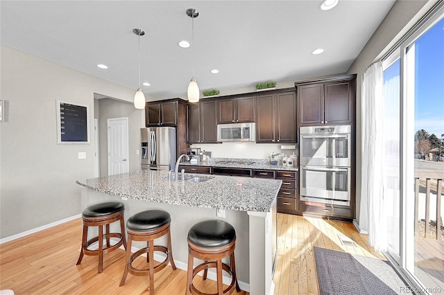 kitchen with stainless steel appliances, dark brown cabinets, sink, and a kitchen breakfast bar