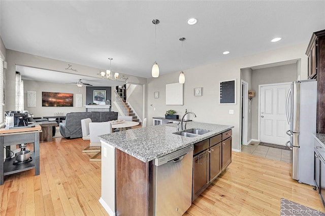 kitchen featuring sink, appliances with stainless steel finishes, dark brown cabinetry, an island with sink, and decorative light fixtures