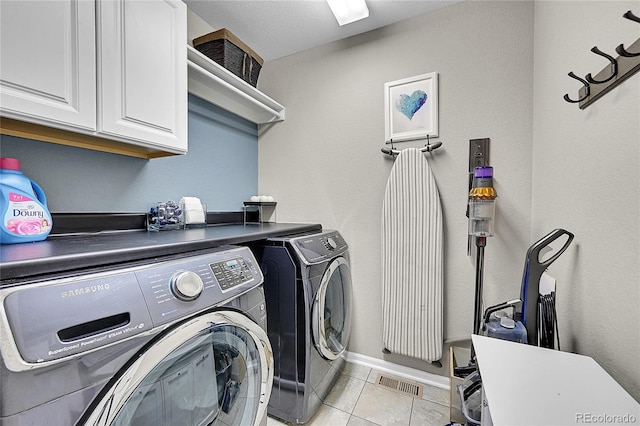 laundry area featuring cabinets, washing machine and dryer, and light tile patterned floors