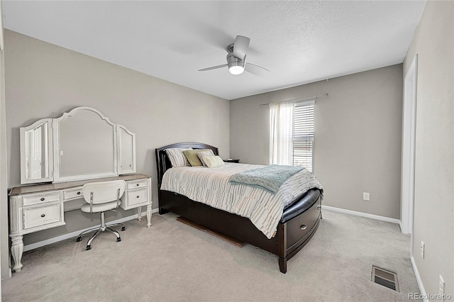 bedroom with light colored carpet, a textured ceiling, and ceiling fan