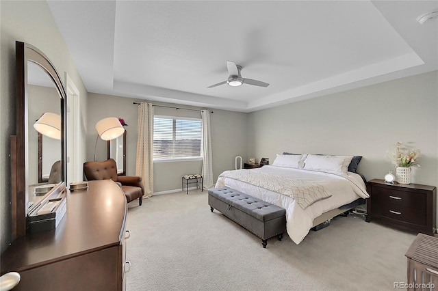 carpeted bedroom featuring a raised ceiling and ceiling fan