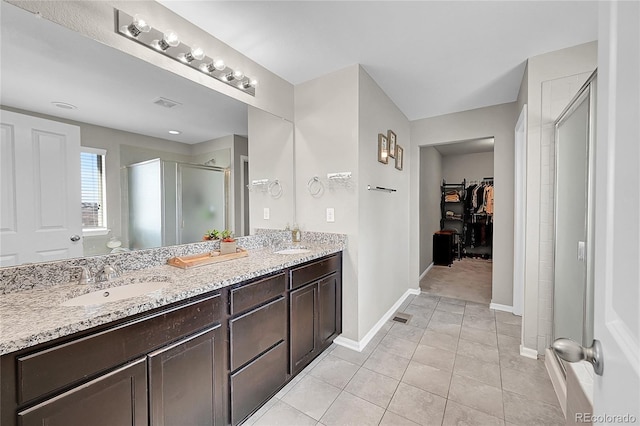 bathroom with walk in shower, vanity, and tile patterned flooring