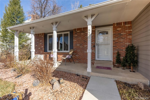 property entrance with a porch and brick siding