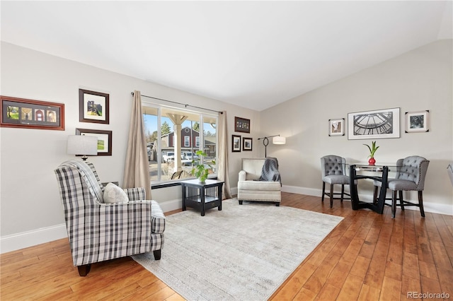 living area with baseboards, lofted ceiling, and wood-type flooring