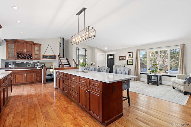 kitchen featuring open floor plan, a breakfast bar, light countertops, lofted ceiling, and light wood-style floors