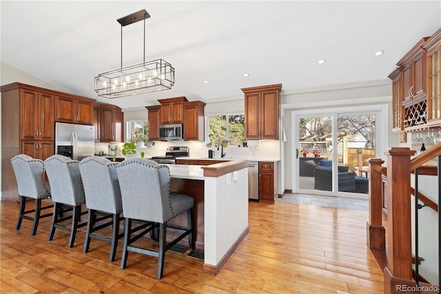 kitchen with light wood-type flooring, a kitchen island, appliances with stainless steel finishes, and light countertops