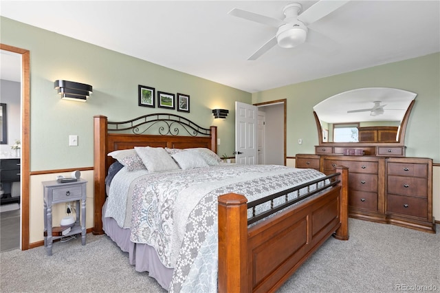 bedroom featuring baseboards, light carpet, arched walkways, and a ceiling fan