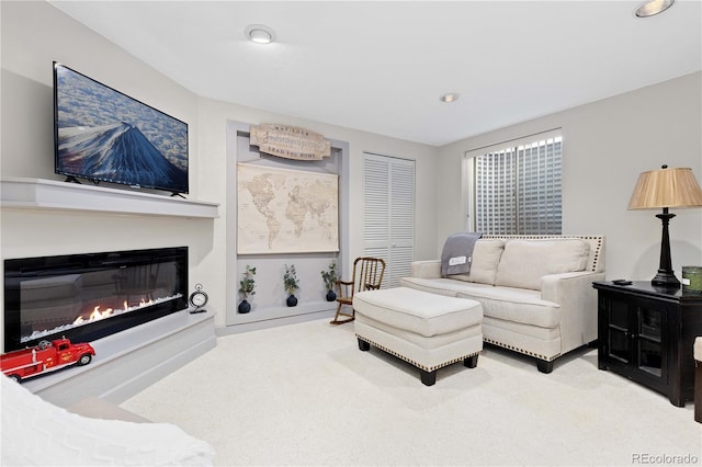 carpeted living room with recessed lighting and a glass covered fireplace