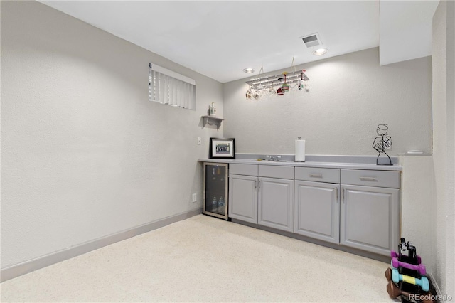 bar featuring bar area, baseboards, beverage cooler, light carpet, and a sink