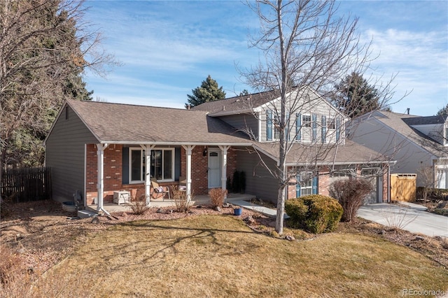 split level home with a front yard, fence, a porch, concrete driveway, and brick siding