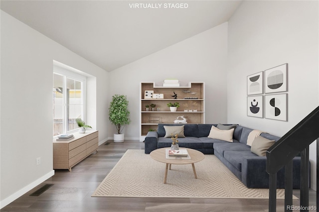 living area with visible vents, wood finished floors, baseboards, and high vaulted ceiling