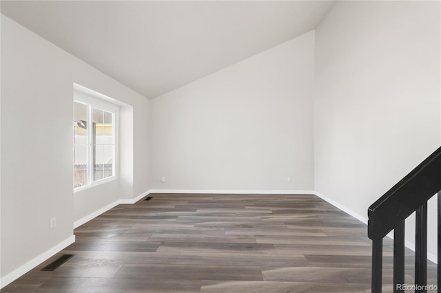 empty room with lofted ceiling, wood finished floors, baseboards, and visible vents