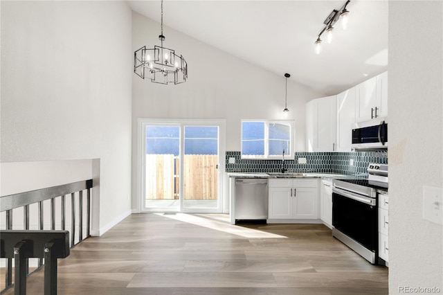 kitchen featuring backsplash, light wood-type flooring, white cabinets, stainless steel appliances, and a sink