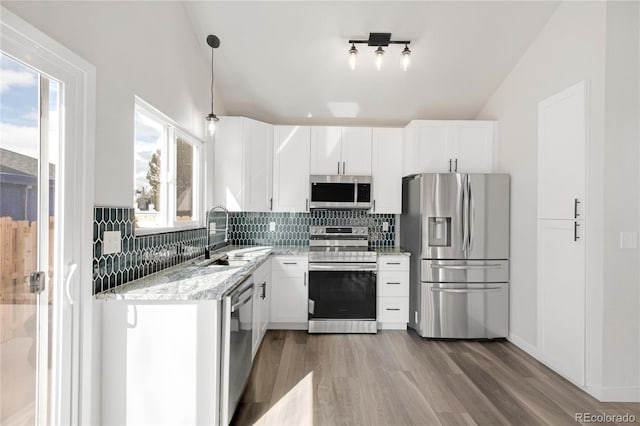 kitchen featuring a sink, tasteful backsplash, wood finished floors, white cabinetry, and stainless steel appliances