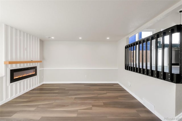 interior space featuring visible vents, baseboards, recessed lighting, a fireplace, and wood finished floors