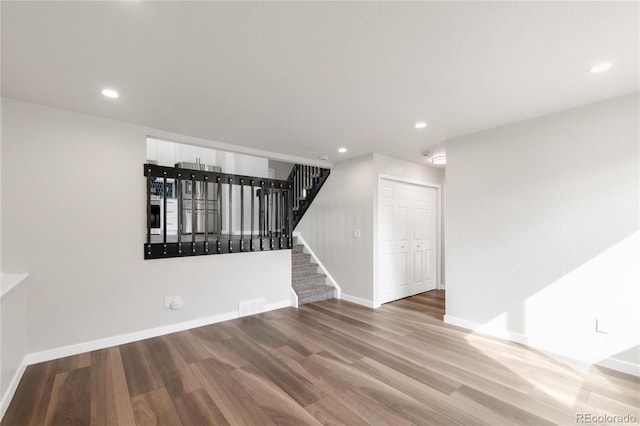 unfurnished room featuring stairway, recessed lighting, wood finished floors, and baseboards