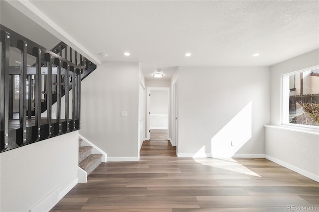 interior space with recessed lighting, baseboards, wood finished floors, and stairs