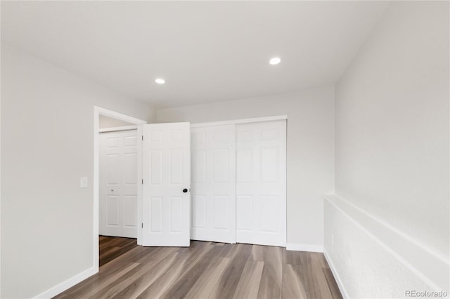 unfurnished bedroom with recessed lighting, a closet, baseboards, and wood finished floors