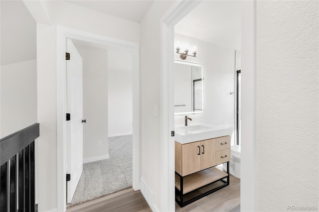 bathroom featuring baseboards, toilet, wood finished floors, and vanity