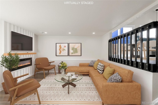 living area with recessed lighting, wood finished floors, and a glass covered fireplace