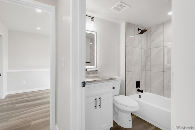 bathroom featuring visible vents, toilet, wood finished floors, shower / bathing tub combination, and vanity