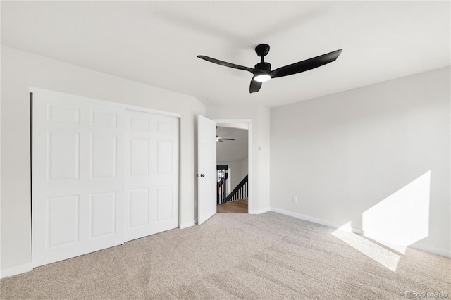 unfurnished bedroom featuring baseboards, a closet, carpet floors, and ceiling fan