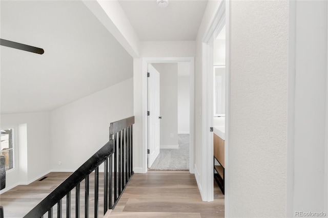 corridor featuring an upstairs landing, light wood-style floors, and baseboards