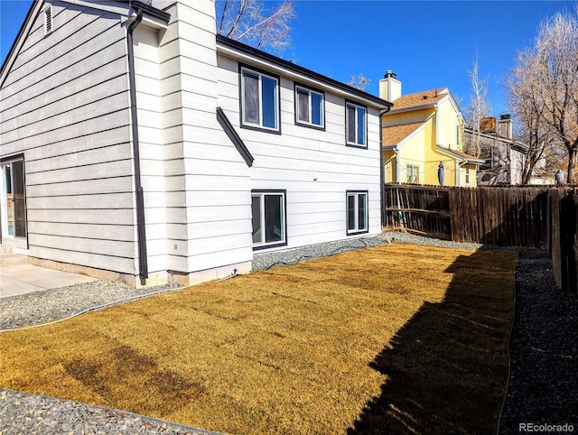 back of property with a lawn, a fenced backyard, and a chimney