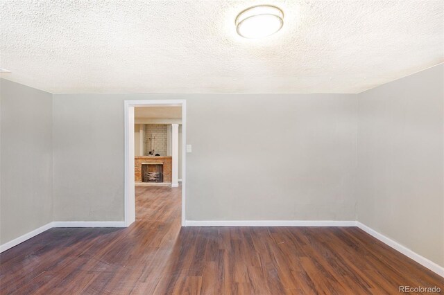 448 K Ave, Limon, CO 80828 - unfurnished room featuring wood finished floors, baseboards, a textured ceiling, and a brick fireplace